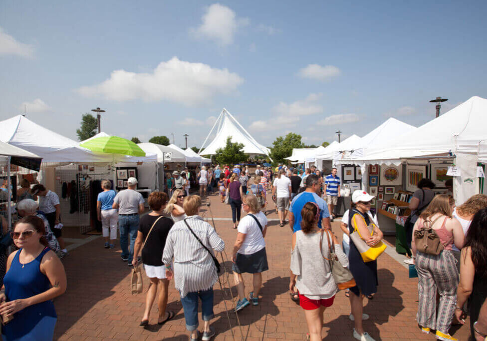 outdoor event people walking through vendor stalls